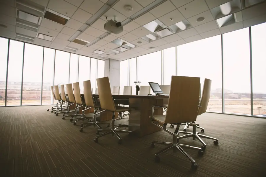 Sala de juntas vacía con una mesa de conferencias larga y ventanales