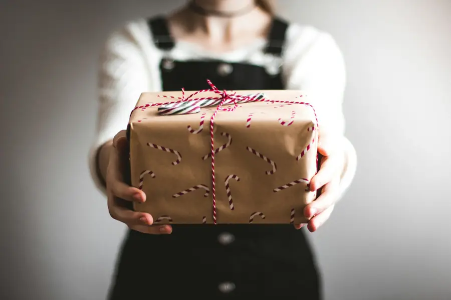Persona sosteniendo una caja de regalo envuelta en papel kraft