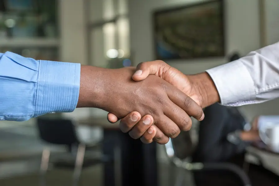 Dos profesionales estrechándose la mano sobre una mesa